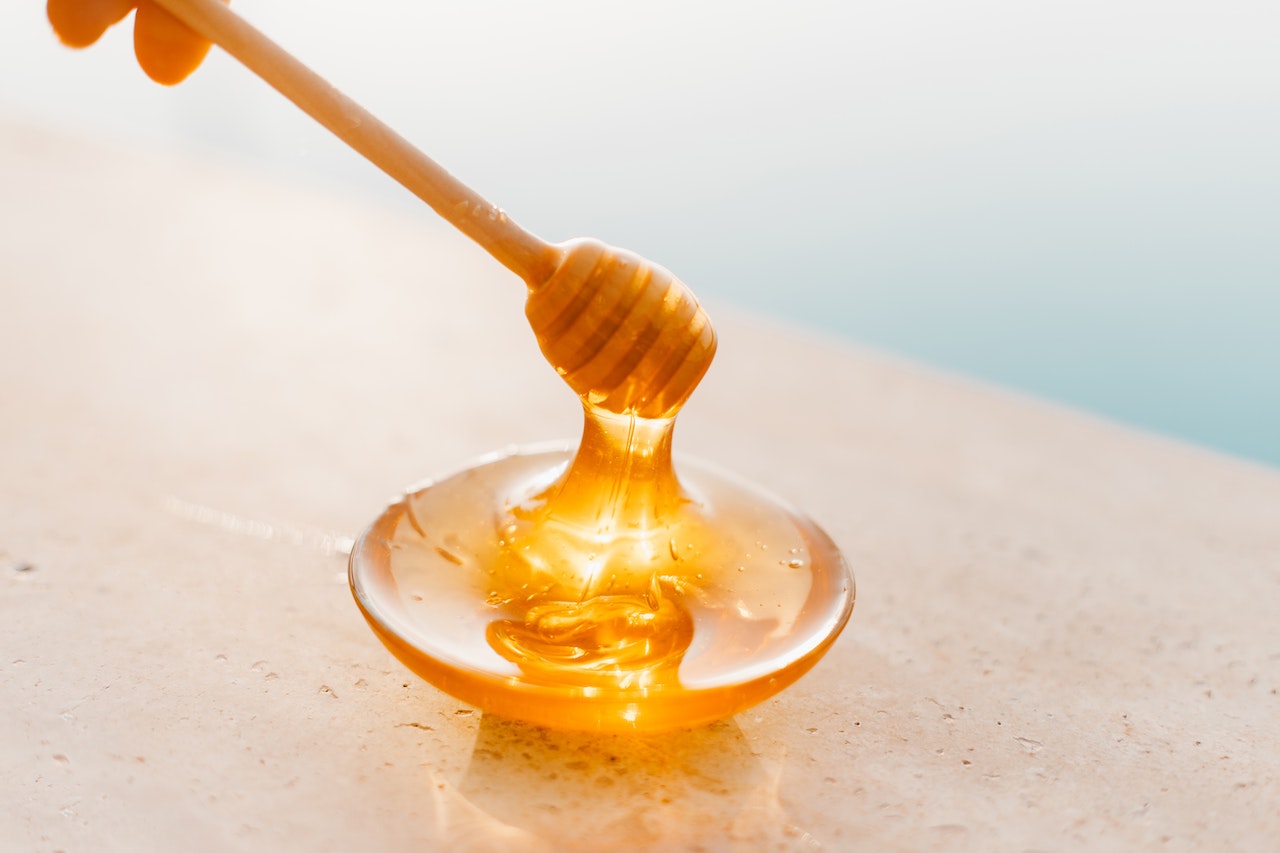 Pot de miel avec une cuillère à miel, produit naturel sucré