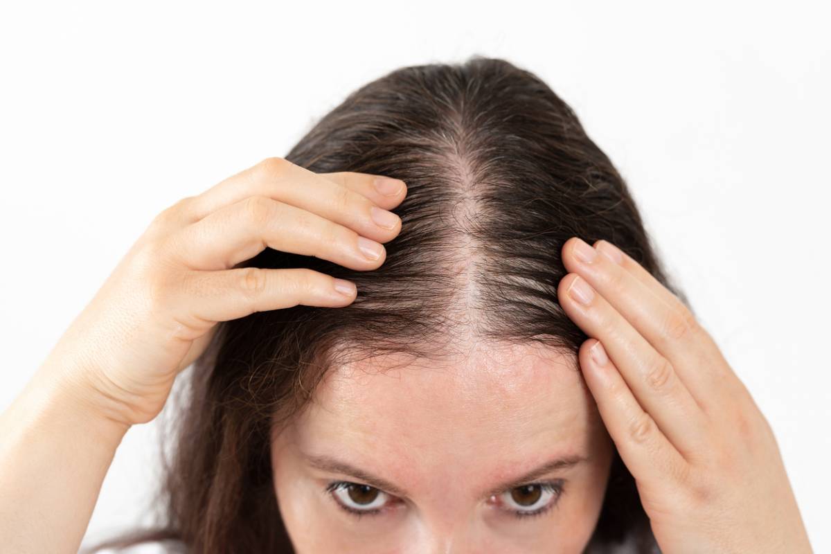 Femme qui regarde sa chevelure, chute de cheveux et nutrition