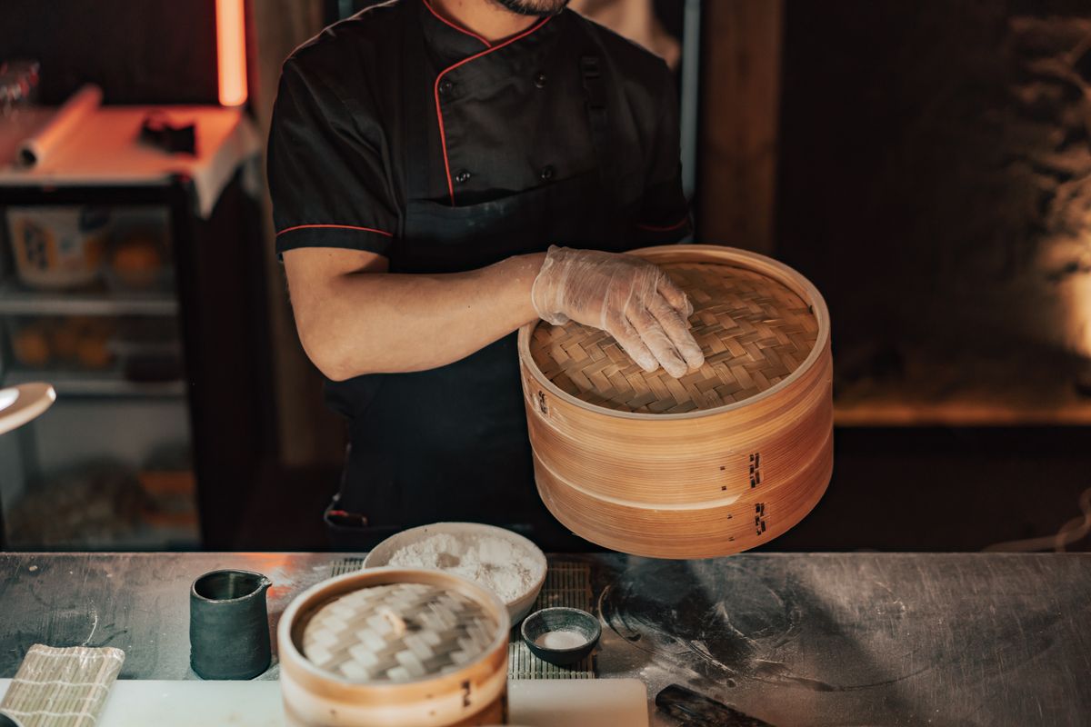 Panier vapeur en bambou sur wok avec légumes verts en train de cuire