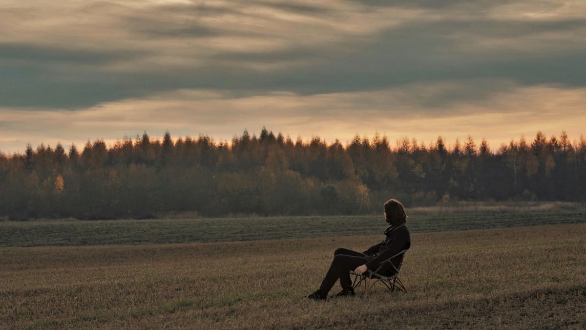 Personne assise seule face à un paysage naturel, moment de calme