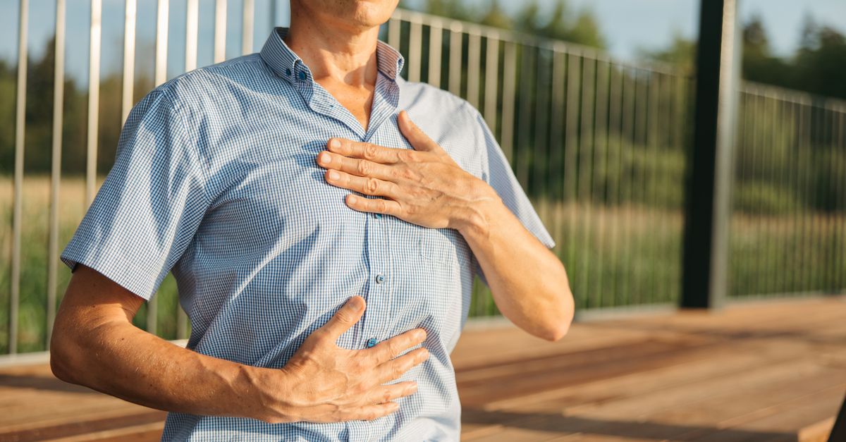 Homme en extérieur pratiquant un exercice de respiration, les mains posées sur la poitrine et le ventre