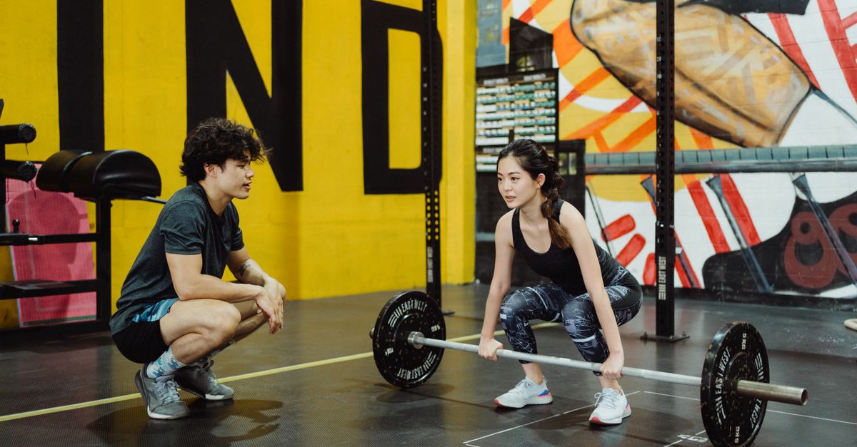 Femme guidée par un coach pendant une séance de musculation en salle de sport