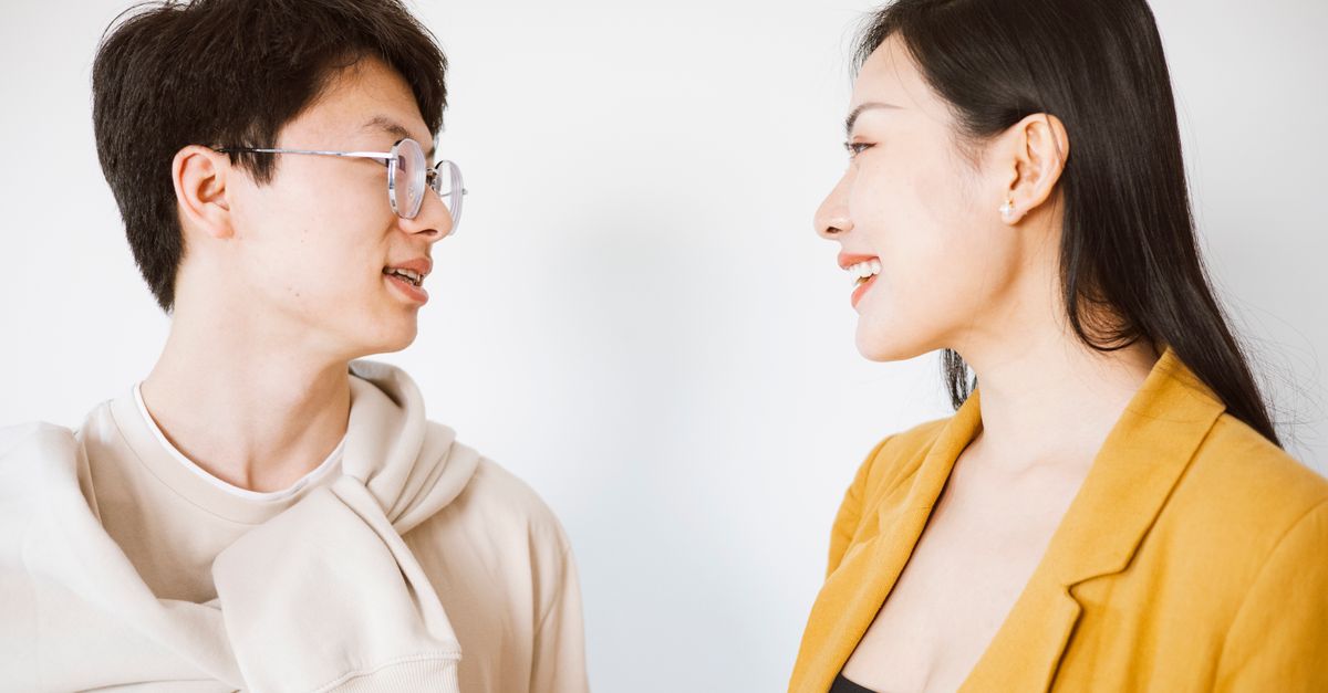 Deux personnes souriantes en pleine conversation détendue dans un lieu lumineux