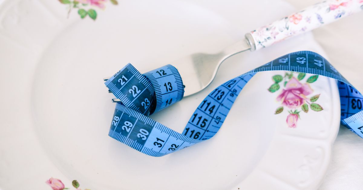 Assiette avec fourchette et mètre ruban de couturière symbolisant l'alimentation et la perte de poids