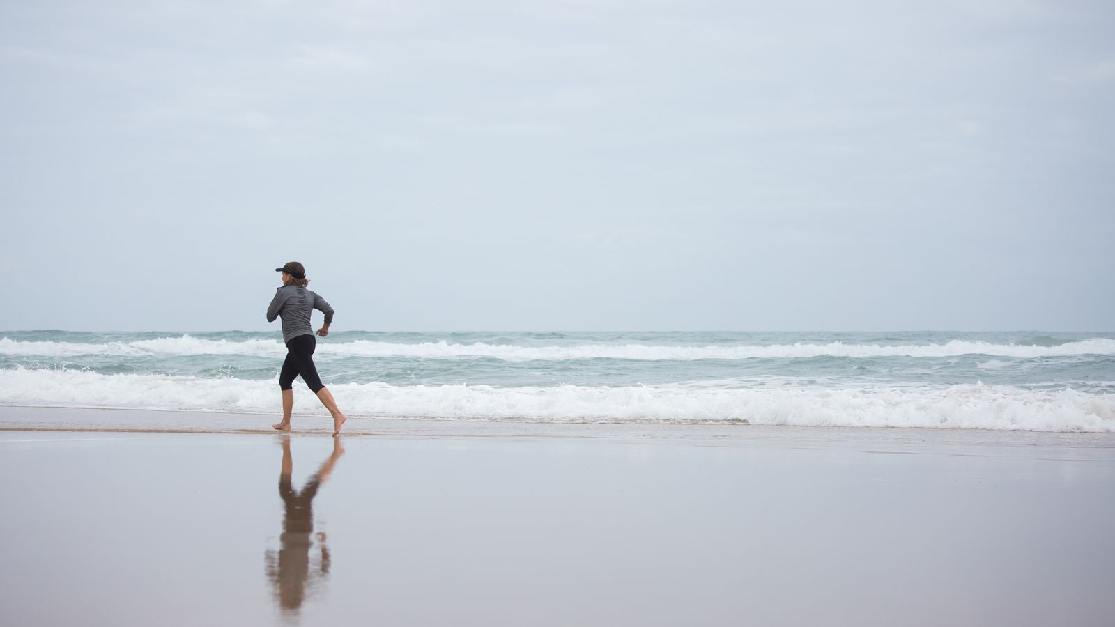 Coureuse en pleine séance de running sur une plage au lever du soleil