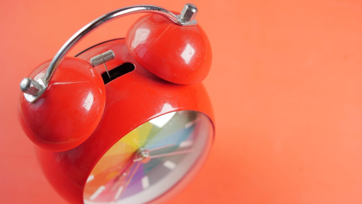 Réveil rouge vintage posé sur fond orange vif