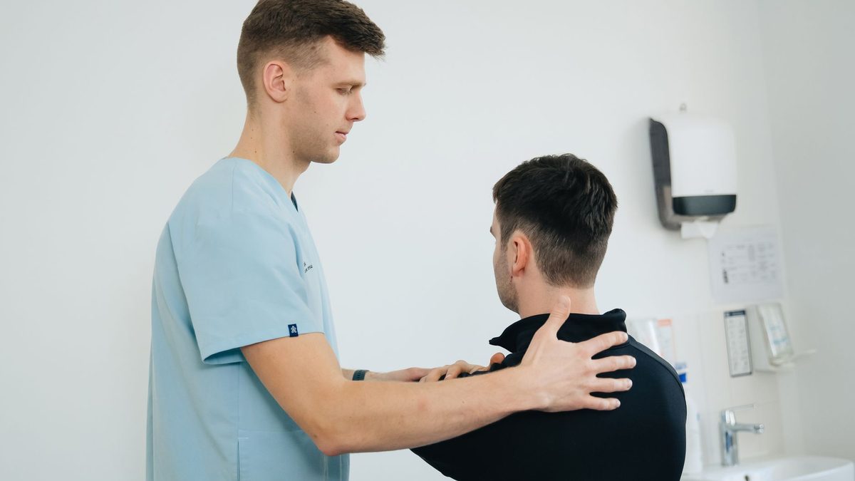 Kinésithérapeute manipulant l'épaule d'un patient allongé en séance de rééducation